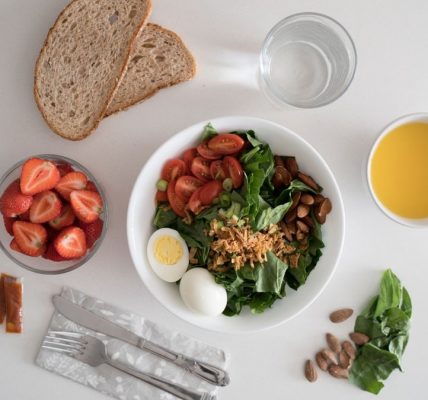 Top view of a nutritious breakfast with salad, eggs, bread, and juice, perfect for a healthy start.